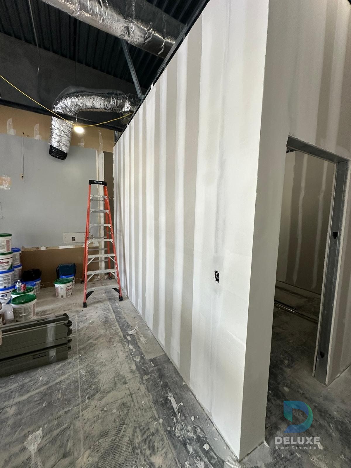 Milan Laser Valrico commercial buildout project with Deluxe Designs & Renovations watermark - Milan Laser Valrico Final Drywall Corridor